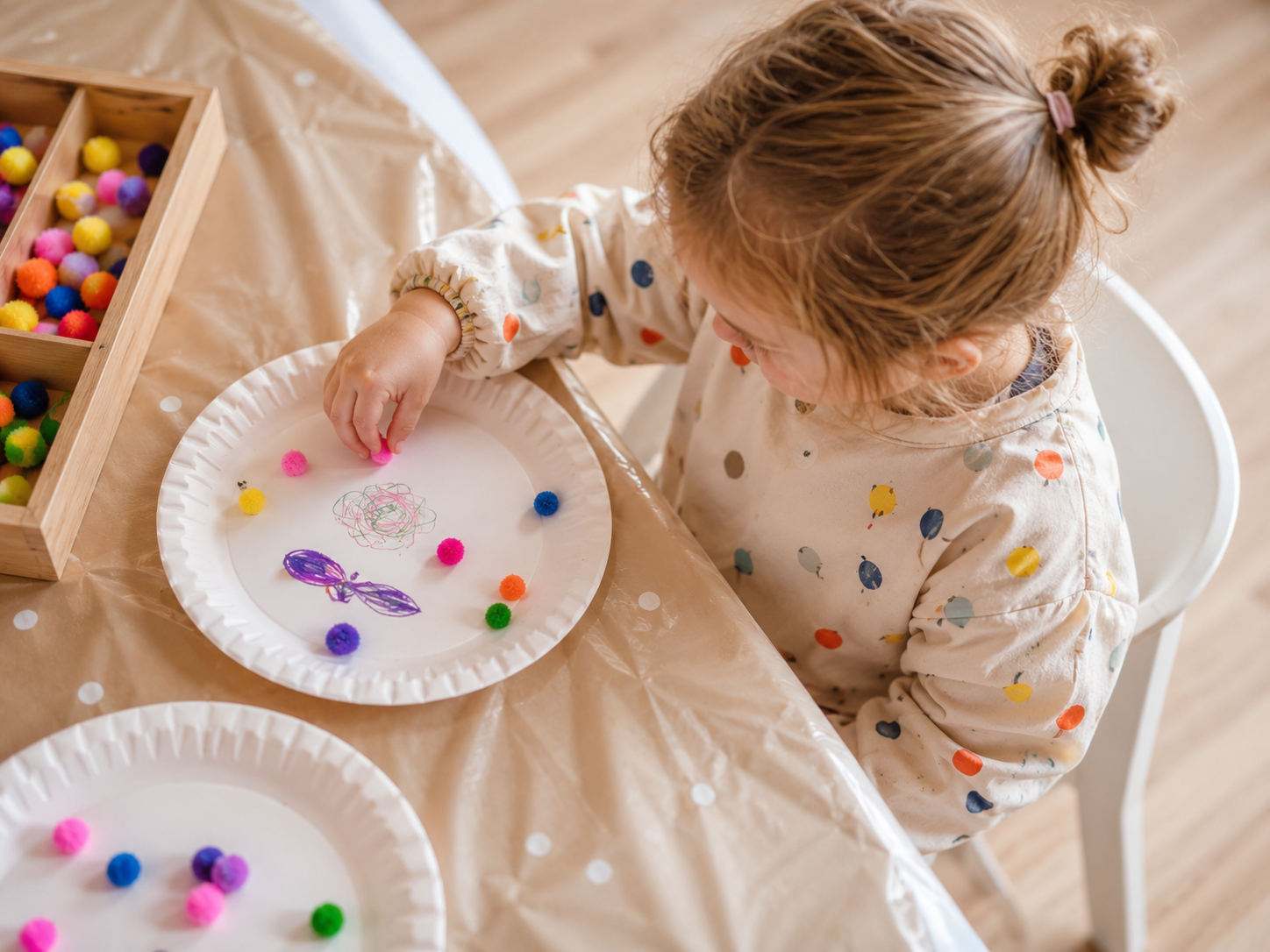 Kind gestaltet ein kreatives Bastelprojekt mit bunten Pompons und Papier.